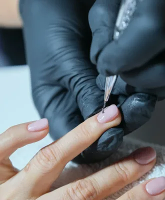 Close-up beautician painting art design on nails.